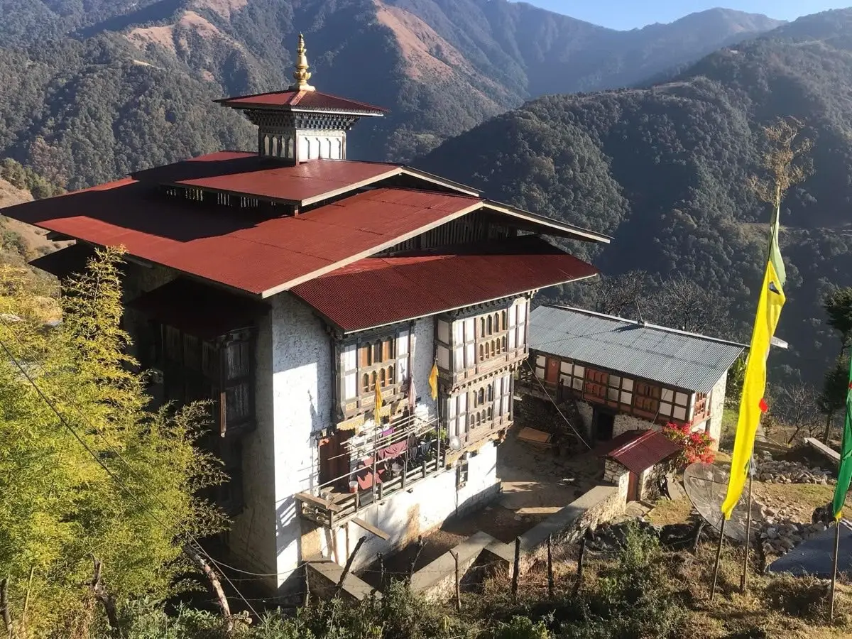 Traditional Bhutanese farmhouse with red roof and painted windows